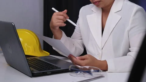 Young female engineer working on laptop, analyzing data in documents in office. Stock Footage 237500933