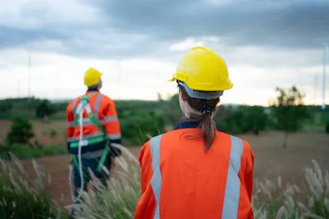 Young female engineer working in a wind turbine field and young man engine... Stock Photos