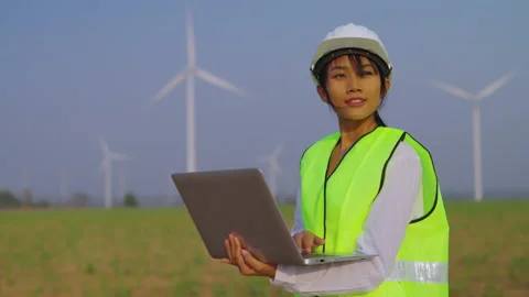 Young female engineering using computer at wind turbine farm. Stock Footage 235548366