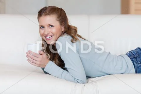Young female enjoying a coffee break on her sofa Stock Photos