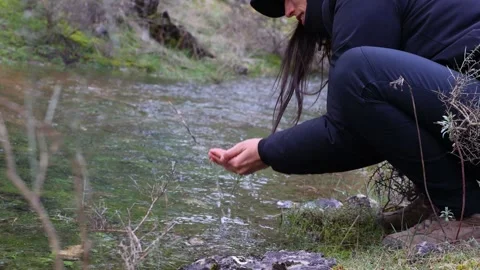 Young Female Explorer Drinking Water from River in Forest Stock Footage 268642615