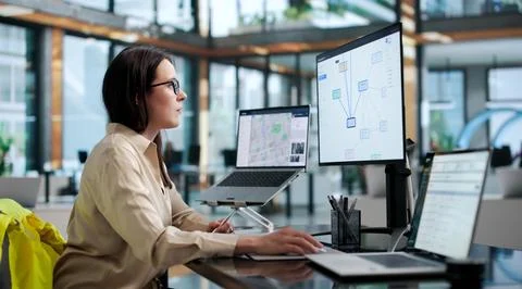 Young Female Forensic Analyst Studies Criminal Network Charts On Laptop. Stock Photos