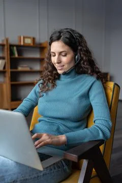 Young female freelancer using headset for remote work, communicating with Photos