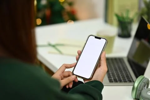 Young female freelancer using mobile phone at desk in living room during Stock Photos