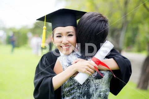 Young female graduate hugging her friend at graduation ceremony Stock Photos