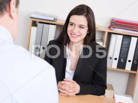 Young female graduate in a job interview at desk Stock Photos