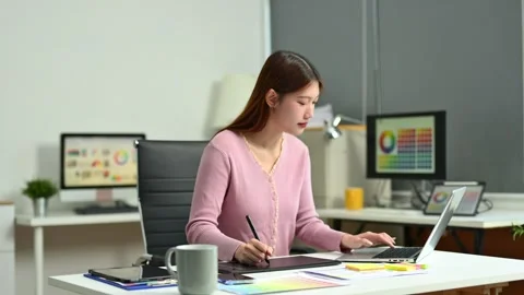 Young female graphic designer using digital tablet and laptop in modern off.. Stock Footage 312436759
