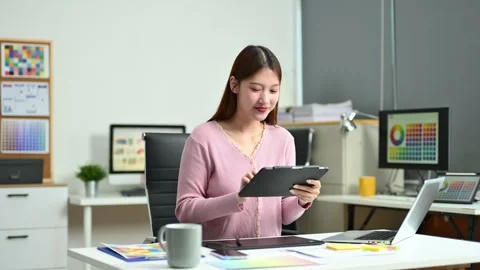 Young female graphic designer using digital tablet and laptop in modern off.. Stock Footage 312436822