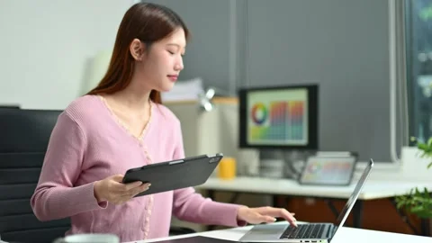 Young female graphic designer using digital tablet and laptop in modern off.. Vídeo Stock 312436845