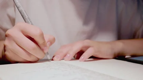 Young female hand using black pen to put thoughts on paper writing on white page Stock Footage 163251832