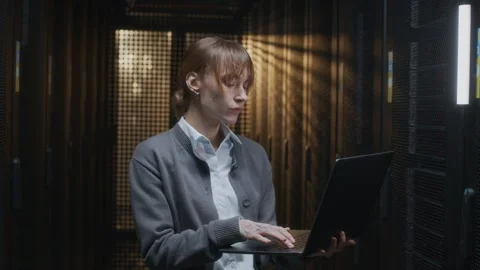 Young Female IT Technician Using Laptop at Rack Server Cabinet Stock Footage 303554850
