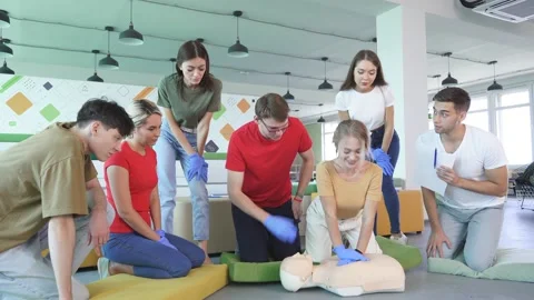 Young female learning how to make first aid heart compressions with dummies Stock Footage 145454001