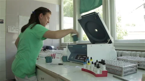 Young female medic technician takes out blood samples from machine for analyses. Video stock 50030153