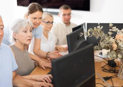 Young female mentor explaining something to elderly woman at computer lesson Stock Photos