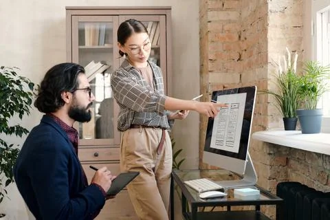 Young female mobile application developer with tablet pointing at sketch Stock Photos