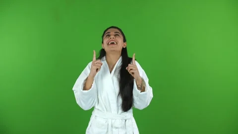 Young female model in bathrobe points her fingers upwards - green screen, chr... Stock Footage 275809562