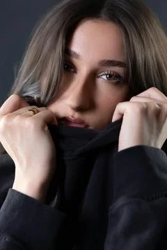Young female model pulling black hoodie up covering face Stock Photos