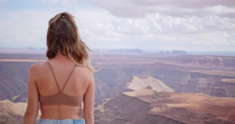 Young female model standing at the edge of a cliff overlooking a canyon Stock Footage 167338308