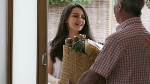 Young Female Neighbor Helping Senior Woman With Shopping Stock Footage