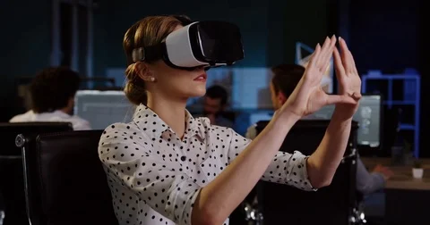 Young female office worker having a VR headset at her workplace in the evening Stock Footage 82446786