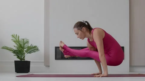 Young female performs acrobatic exercises hands on red mat in stodio Stock Footage 248308548