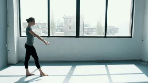 Young female performs a backflip with hands in the dance stodio Flexible woman Stock Footage 107332324