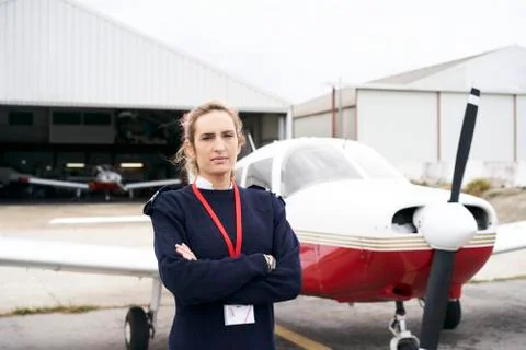 Young female pilot posing in front of her plane. Stock Photos