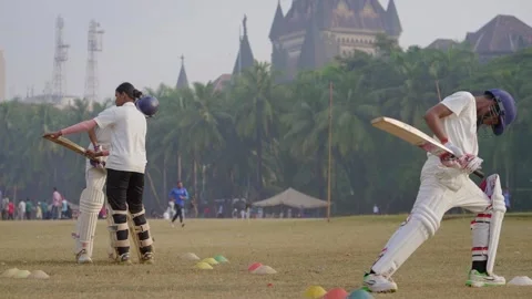 A young female player train to bat two male cricket aspirants in Mumbai Stock Footage 326756829