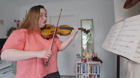 Young female playing string instrument, reading musical notes, slow-mo Video stock 274251457