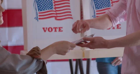 Young female poll worker processing a male voter with a digital tablet Stock Footage 274993725