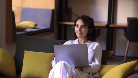 Young female professional working on computer device. Sitting on sofa with Stock Footage 137095106