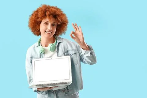 Young female programmer with blank laptop showing OK on blue background Stock Photos