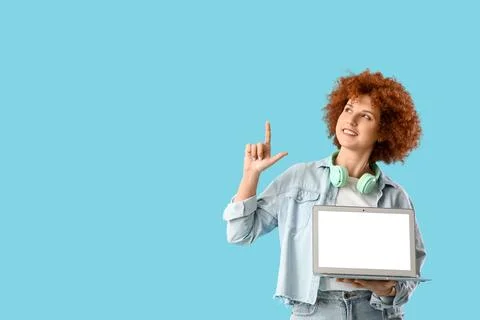 Young female programmer with blank laptop pointing at something on blue backg Stock Photos