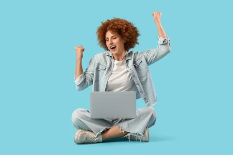 Young female programmer with laptop celebrating success on blue background Stock Photos