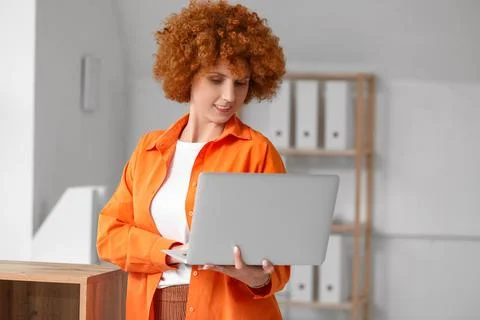 Young female programmer with laptop in light office Stock Photos