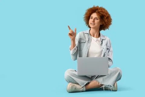 Young female programmer with laptop pointing at something on blue background Foto stock