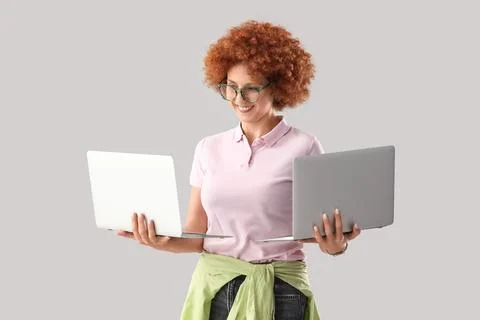 Young female programmer with laptops on grey background Stock Photos