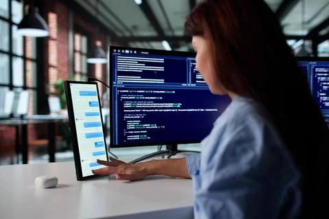 Young Female Programmer Multitasking On Multiple Screens In Modern Apartment. Stock-Fotos