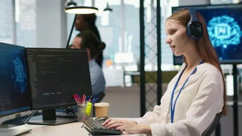 Young female programmer in office reviewing AI system metrics, listening music Stock-Footage 313014731