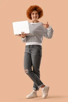 Young female programmer pointing at laptop on beige background Stock Photos