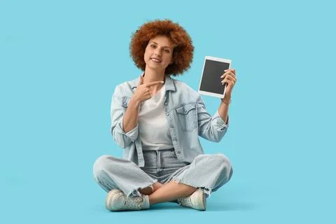 Young female programmer pointing at tablet computer with blank screen on blue Stock Photos