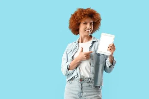 Young female programmer pointing at tablet computer with blank screen on blue Foto stock