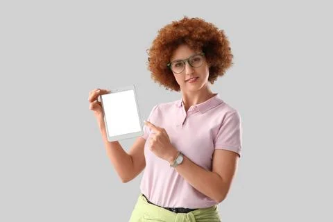 Young female programmer pointing at tablet computer with blank screen on grey Stock Photos
