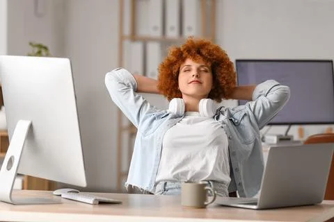 Young female programmer resting at her workspace in office Stock Photos