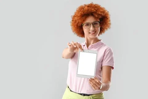 Young female programmer showing tablet computer with blank screen on grey bac Stock Photos