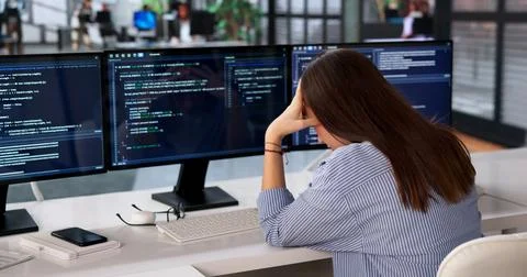Young Female Programmer Sits At Desk, Feeling Bored And Frustrated Coding. Stock-Fotos