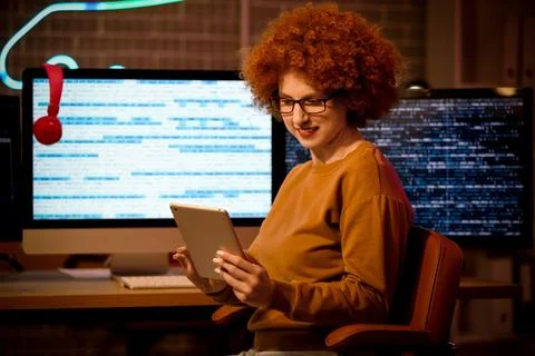 Young female programmer with tablet computer at her workspace in office at ni Foto stock
