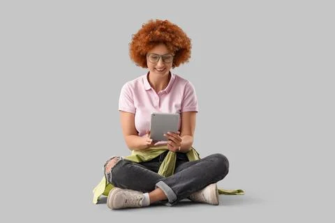 Young female programmer with tablet computer sitting on grey background 写真素材