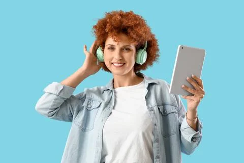Young female programmer with tablet computer and headphones on blue backgroun Stock-Fotos