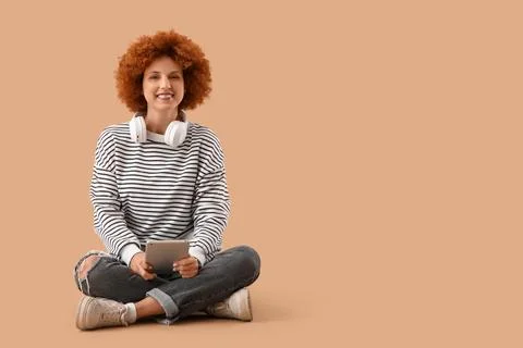 Young female programmer with tablet computer sitting on beige background Stock Photos